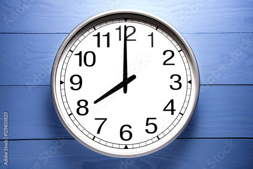 Round clock shows shows at 8 o'clock, clock on blue background