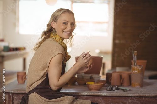 Beautiful female potter painting on pot