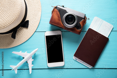 creative Flat lay travel concept with camera, mobile phone and hat on blue wooden table background