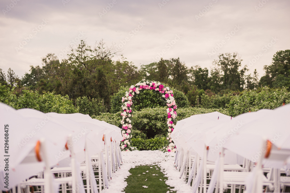Stylish traditional floral decoration with peonies at wedding ceremony, umbrellas on the chairs