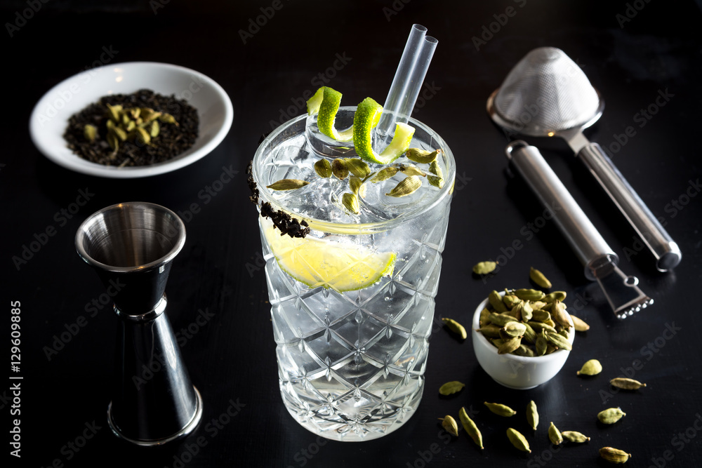 Gin tonic drink cocktail fancy glass black background tonic water ice garnish fresh fruit craft cocktail cucumber orange peel decoration measure bottle lime peeler grapefruit