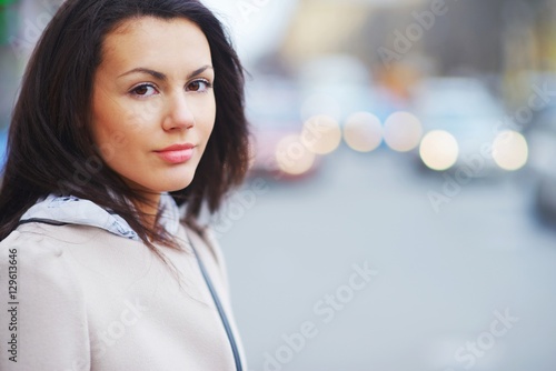 Obraz na plátne Portrait of a young brown-eyed brunette girl on a beautiful blurred background city street, close-up