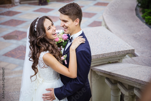 Fototapeta Happy young bride and groom going outdoors