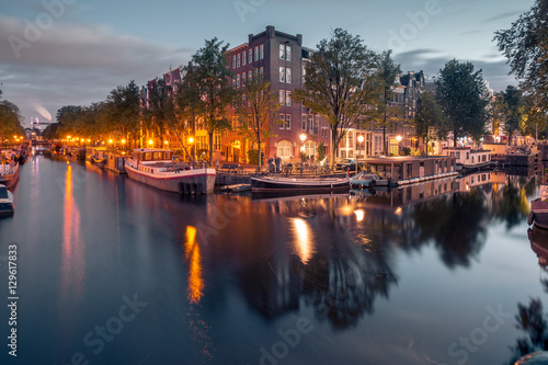 Amsterdam canals and typical houses  boats and bicycles during evening twilight blue hour  Holland  Netherlands.