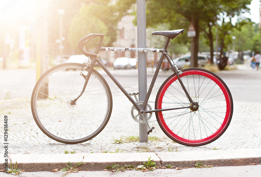 Bicycle parked against a pole with sun flare