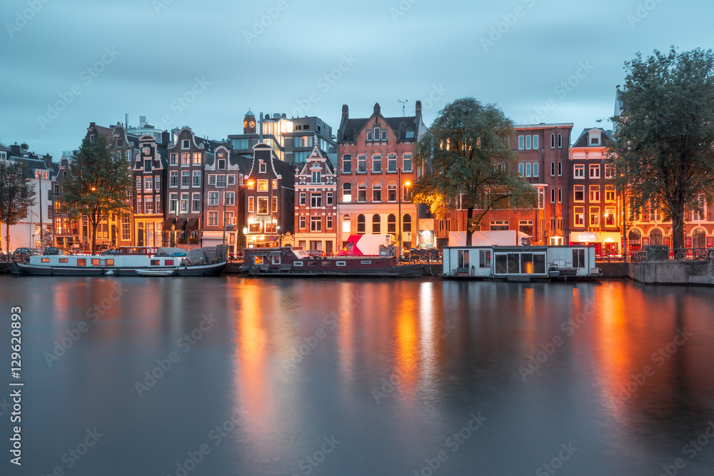 Fototapeta premium Amsterdam canal Amstel with typical dutch houses and boats during twilight blue hour, Holland, Netherlands.