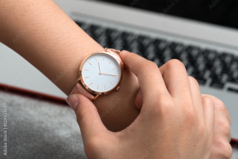 Wrist watch on girl's hand in front of a desk with notebook comp Wrist watch on girl's hand in front of a desk with notebook comp