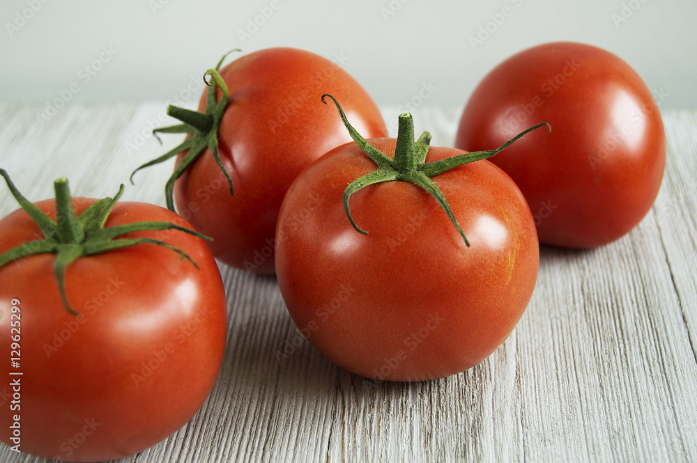 four red tomatoes scattered on wood table four red tomatoes scattered on wood table