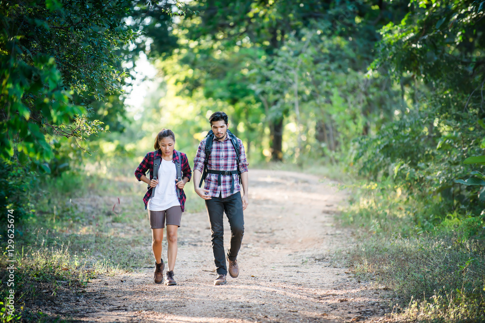 Obraz premium Young couple walking with backpacks in forest. Adventure hikes,
