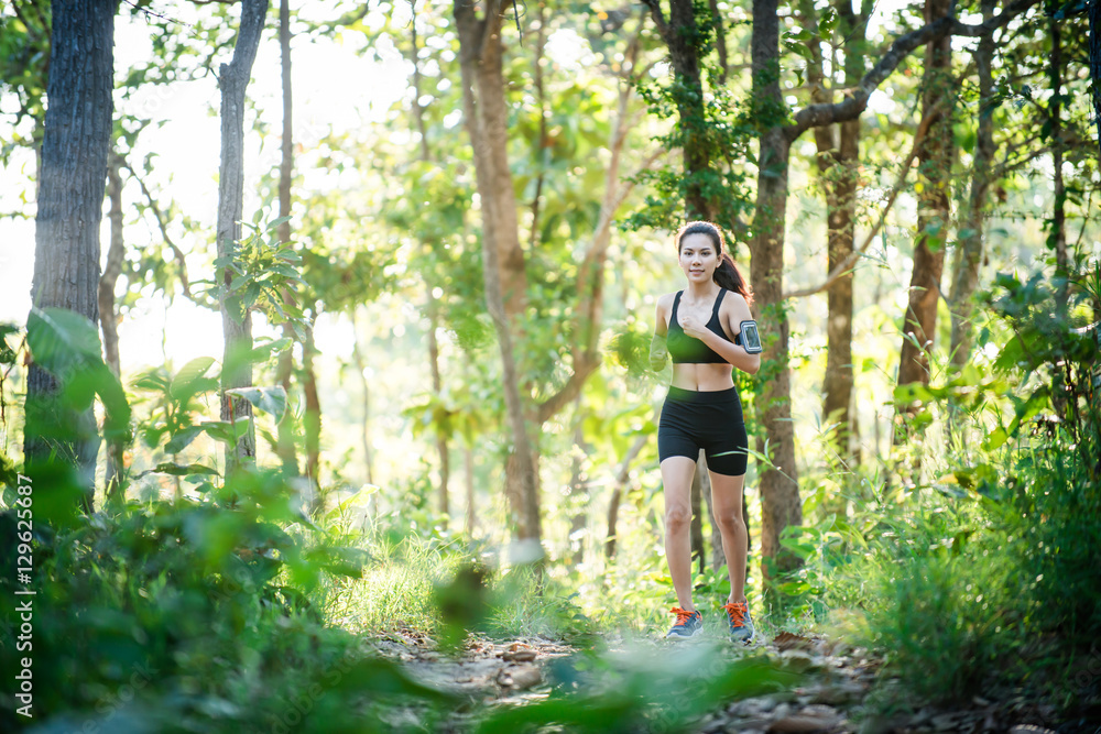 Young woman jogging on rural road in green forest nature. Young woman jogging on rural road in green forest nature.
