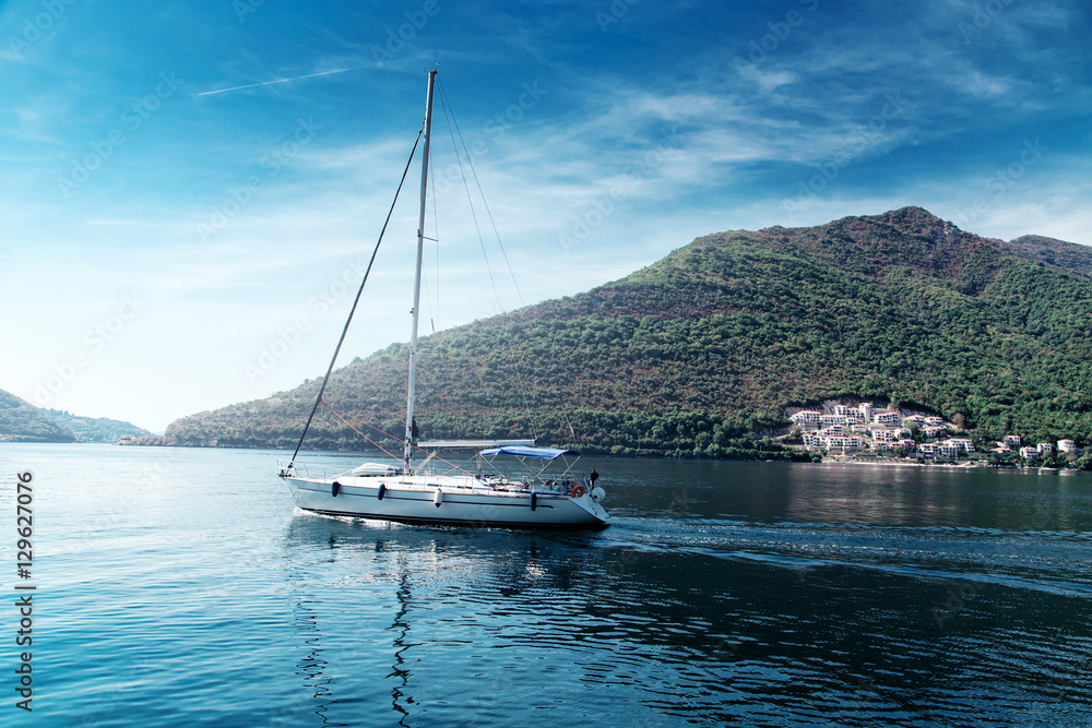 Sailing yacht swimming at blue sea near forest mountains Sailing yacht swimming at blue sea near forest mountains