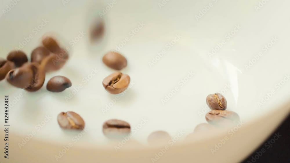 Coffee beans. Extreme close up slow motion shot of coffe beans falling onto a coffee bean mound against a white background or plate Coffee beans. Extreme close up slow motion shot of coffe beans falling onto a coffee bean mound against a white background or plate