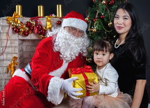 Santa Claus and mother with your child in a dress. Christmas Scenes.