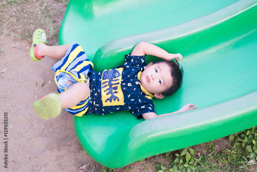 Fototapeta premium Little Asian kid playing slide at the playground.