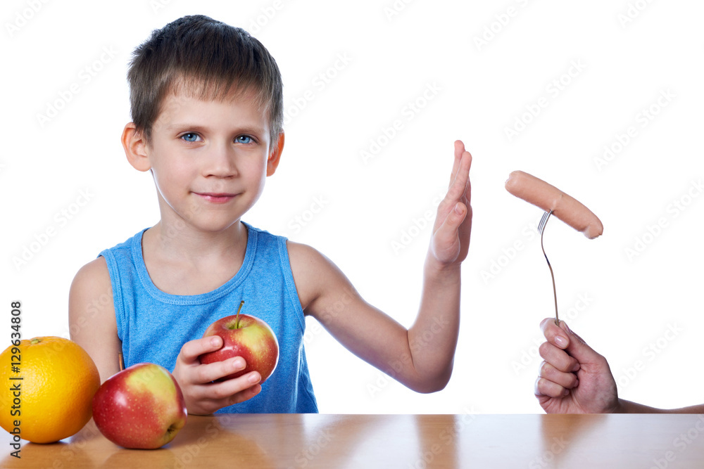 Boy with apples and orange against harmful sausage Boy with apples and orange against harmful sausage