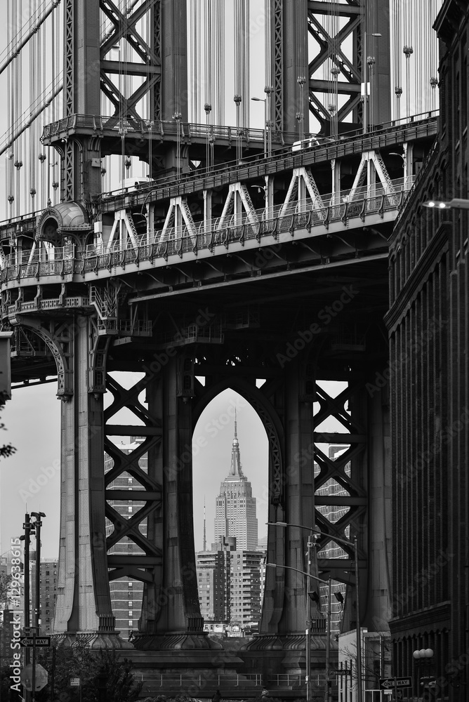 Black and White image of Empire state building through Brooklyn Bridge