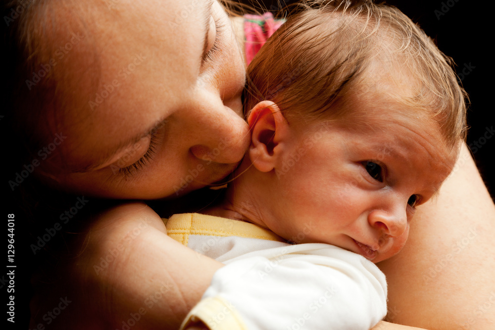 Young mother holding her baby boy. Isolated on black background Young mother holding her baby boy. Isolated on black background