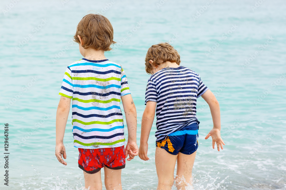 Two little kids boys running on the beach of ocean Two little kids boys running on the beach of ocean
