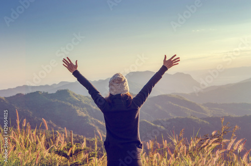 Carefree Happy Woman Enjoying Nature on grass meadow on top of mountain cliff with sunrise. Beauty Girl Outdoor. Freedom concept.