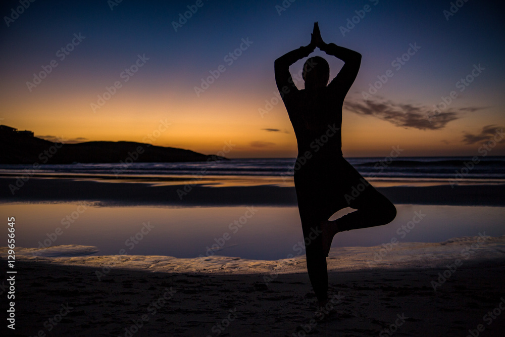 Yoga pose sillhouette on the beach at sunset