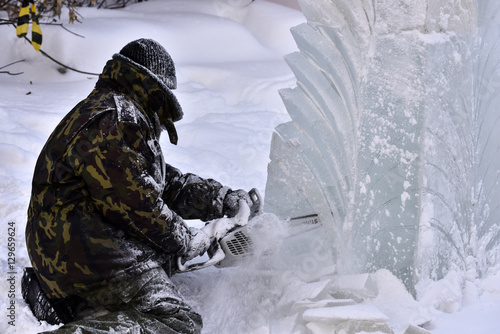 Worker using a chainsaw carving an ice sculpture