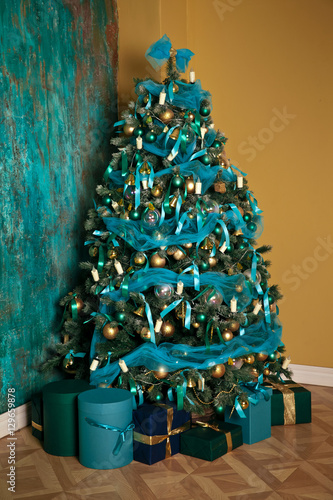 Green New Year tree decorated with toys and balls. Christmas background with grunge plaster wall photo