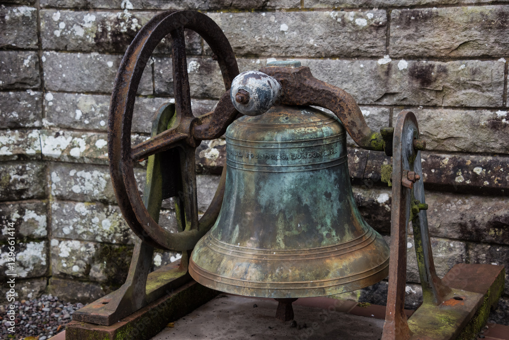 An old rusty disused church bell located in front of an old church