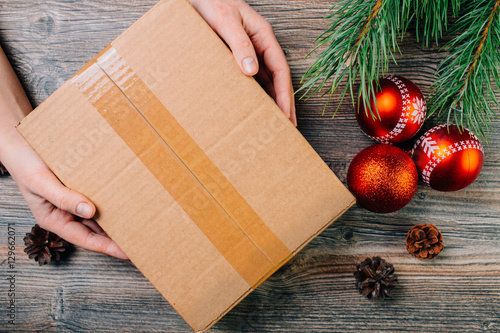 A girl holding a box over the table. Parcel delivery. Christmas background.