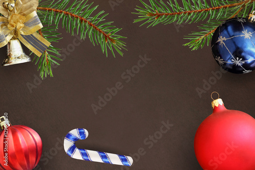 Christmas branches of spruce, stick, blue and red wavy dull balloon and decorative bell on dark background photo