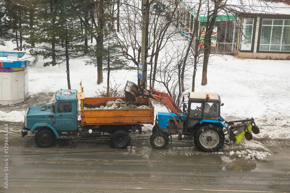 Tractor loads snow on the dump truck.