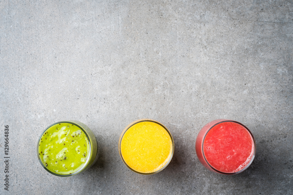 Glasses of fresh juice on gray stone table Glasses of fresh juice on gray stone table