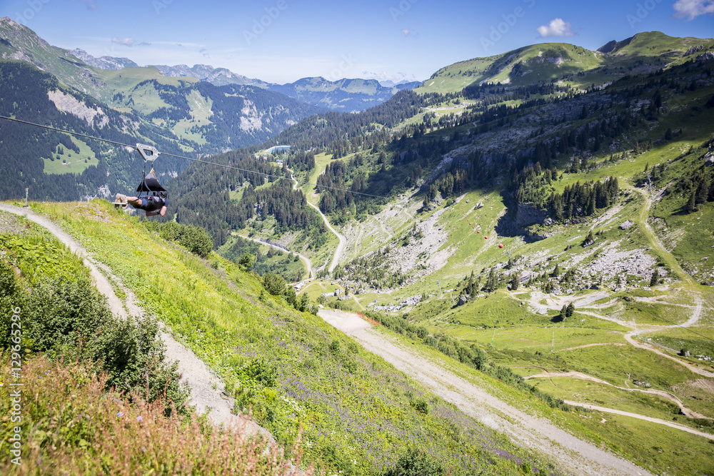 Man going for an extreme Zip-line flight over the alpine landscape in summer, Alps mountain massif, Cantons Vaud and Valais, Swiss Alps, Switzerland