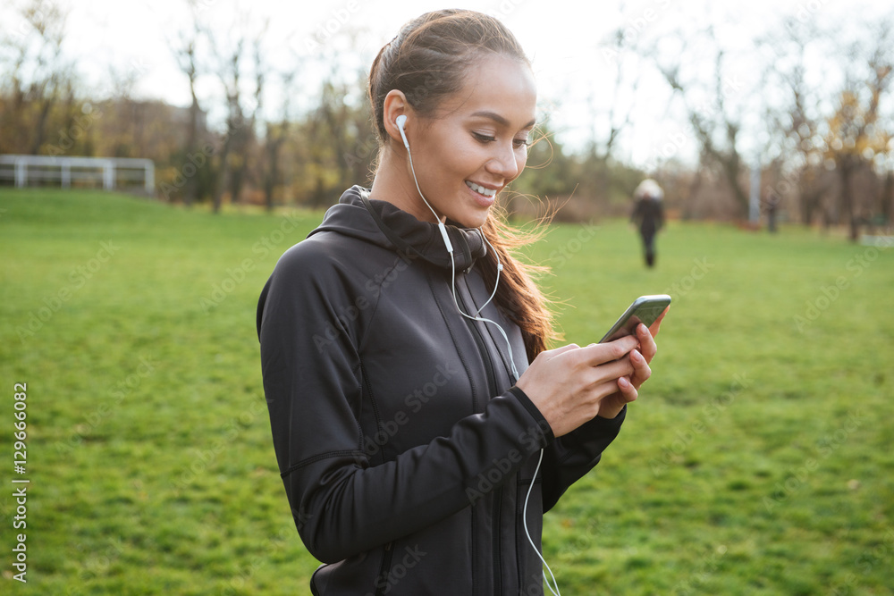 Cheerful female runner using her phone outdoors Cheerful female runner using her phone outdoors