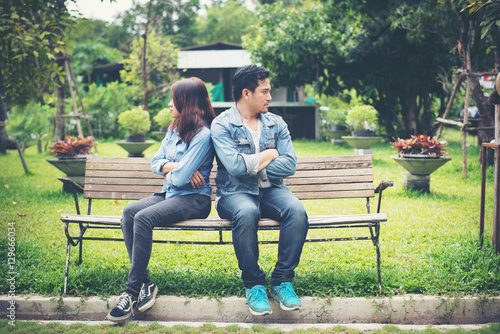 Displeased young couple sitting on bench in park, Couple lifesty