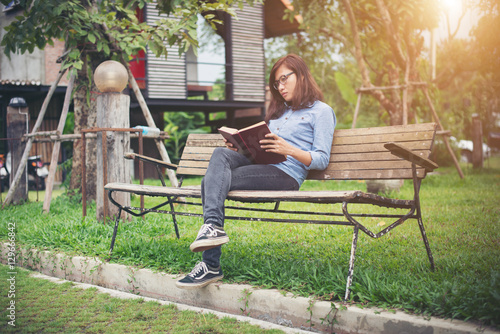 Hipster charming girl relaxing in the park while read book, Enjo