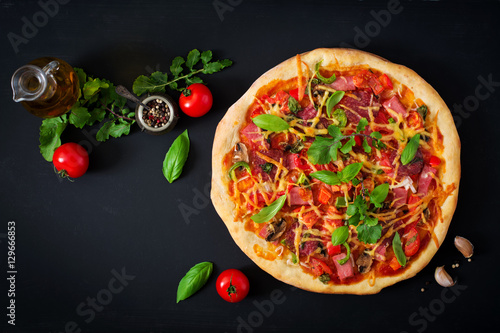 Pizza with salami, ham, tomato, cheese and mushrooms. Top view