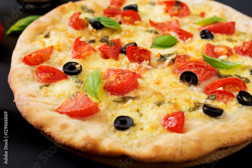 Pizza with tomato, mozzarella, basil and olives.