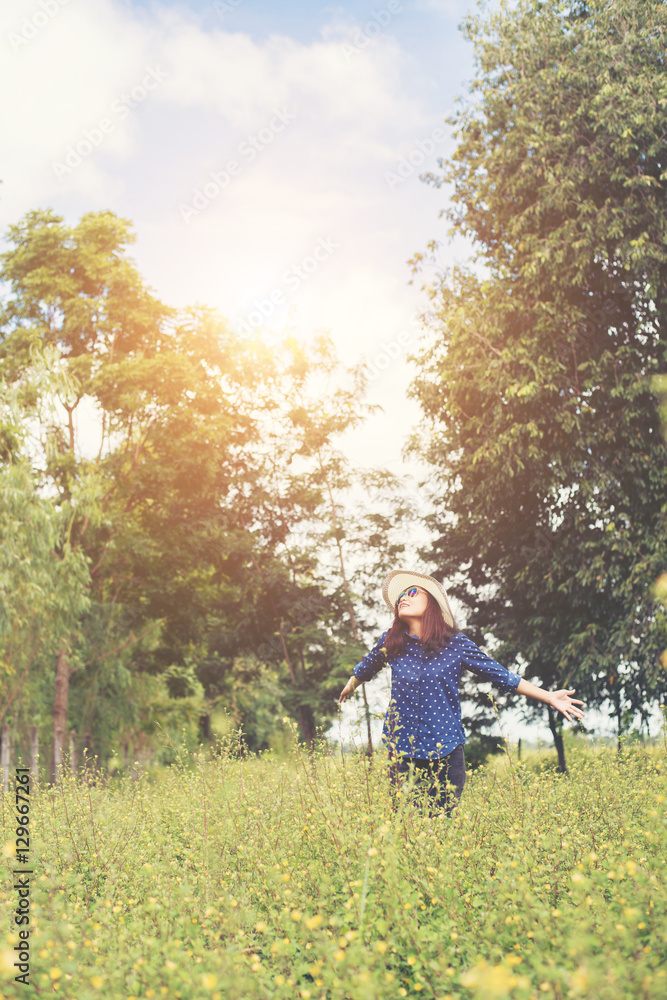 Fototapeta premium Attractive young woman standing in a field of yellow flowers, ha