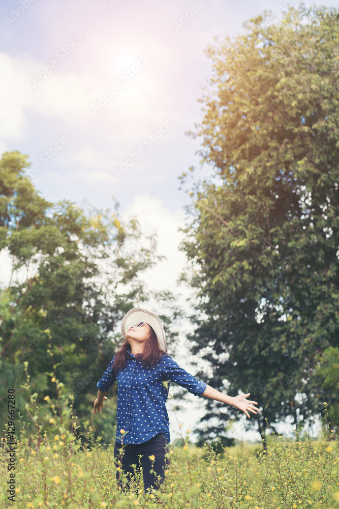 Attractive young woman standing in a field of yellow flowers, ha Attractive young woman standing in a field of yellow flowers, ha