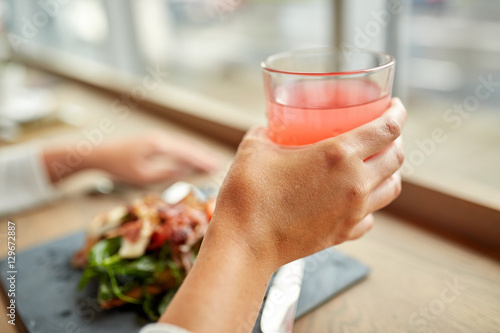 hand with glass of juice and salad at restaurant