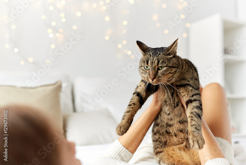 young woman with cat lying in bed at home
