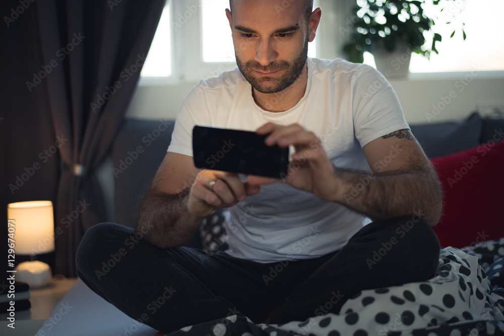 Portrait of a male using his smartphone in his bedroom
