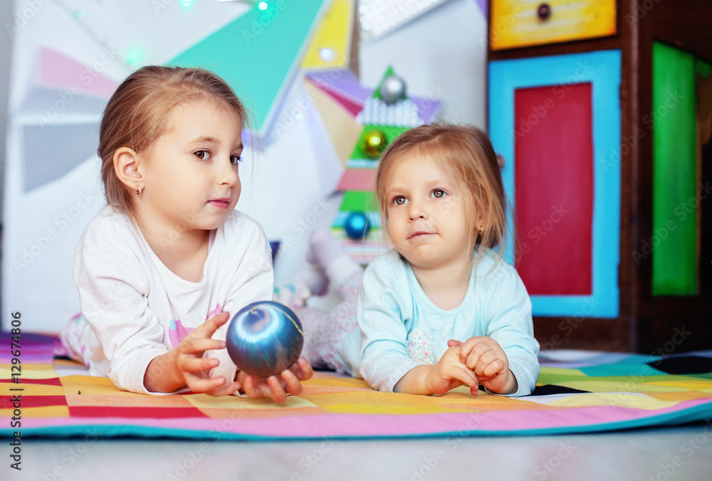 Fototapeta premium Two sisters lying flat. Christmas concept and lifestyle.