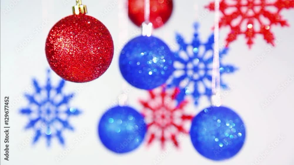 Christmas and New Year blurry blue and red bright color shining beautiful balls and snowflakes hanging on silver ropes at white background. Real time full hd video footage. Christmas and New Year blurry blue and red bright color shining beautiful balls and snowflakes hanging on silver ropes at white background. Real time full hd video footage.