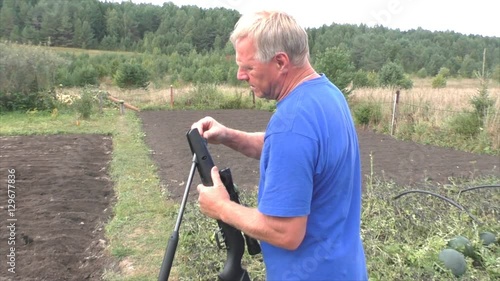 Elderly man shooting a gun on nature
 photo