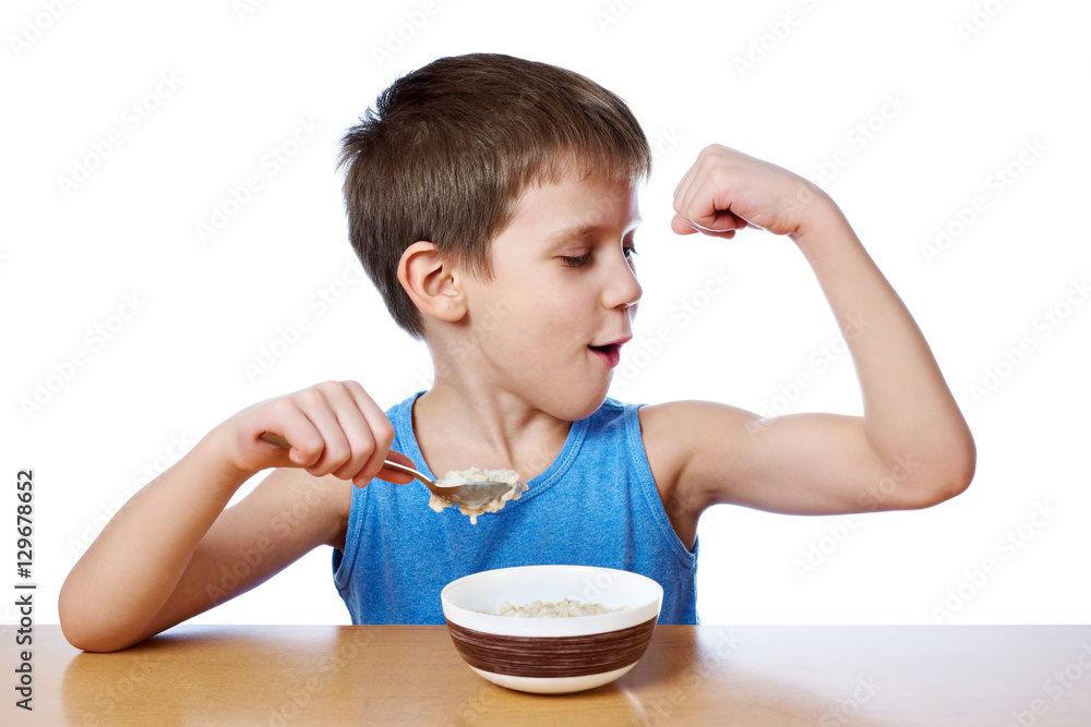 Happy boy eating porridge at table isolated Happy boy eating porridge at table isolated