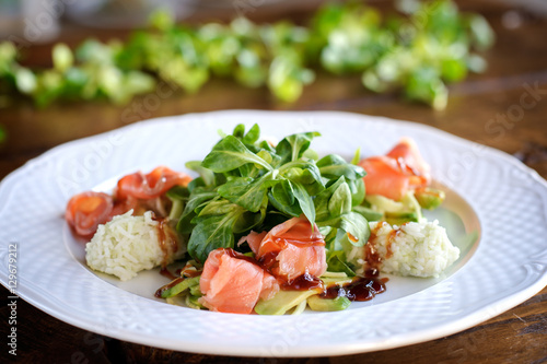 finest dining salad with smoked salmon, rice, herbs and avocado in white plate