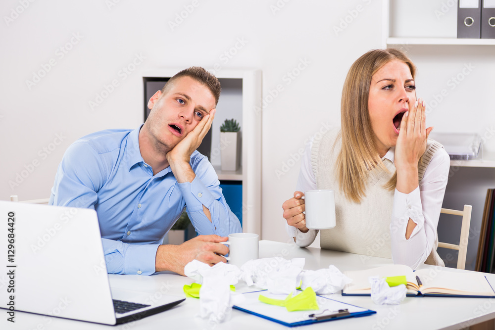 Exhausted businessman and businesswoman drinking coffee at their office.
Exhausted businessman and businesswoman drinking coffee at their office.