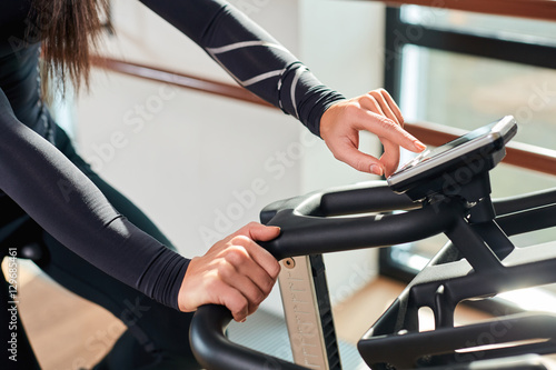 Woman hands on a bar stationary bike the gym