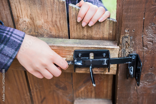 Young woman opening lock on wooden door